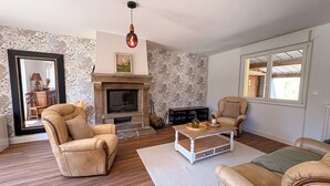 Una sala de estar con chimenea, sofás de cuero, una mesa de centro y papel tapiz estampado.