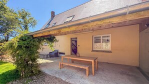 Una casa con un banco de madera, una puerta y un ventanal.