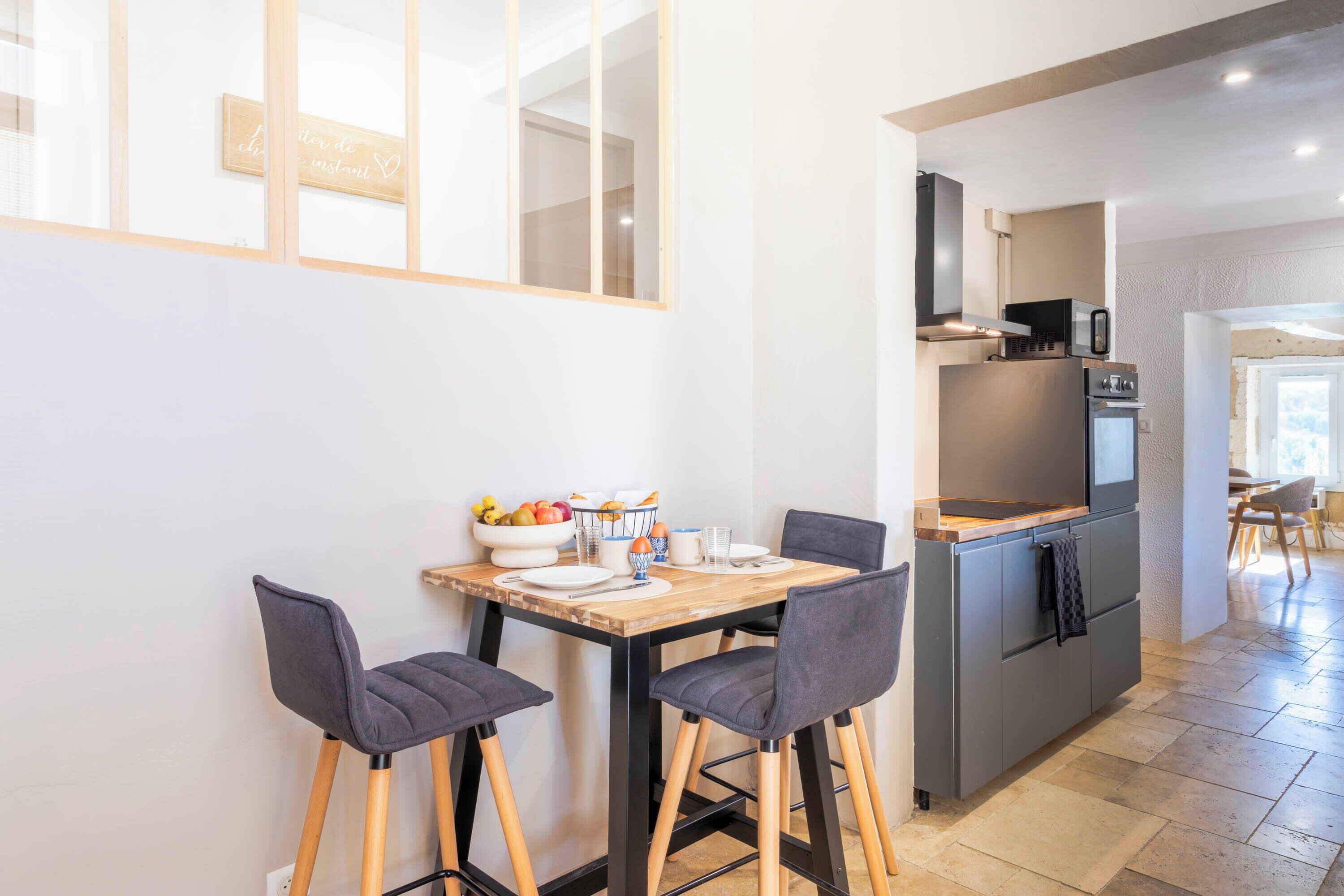 Eine moderne Küche mit Essbereich, ausgestattet mit einem Holztisch, zwei Stühlen und einem eingebauten Backofen.