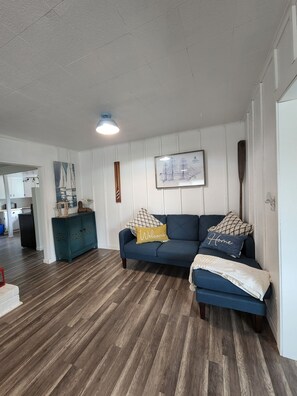 A living room with a dark blue sofa, a teal cabinet, and a wooden floor. - 4 blocks to beach. Dog Friendly. Fenced Yard. In Pacific Beach. Arcade! (Pacific Beach)