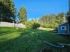 Ein Garten mit Holzzaun, kleiner Gartenhütte und Rasenfläche.