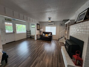 Ein Zimmer mit Kamin, einer Couch, Holzboden und einer Tür mit der Aufschrift 'BEACH'.