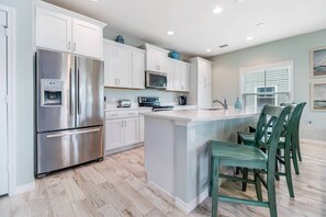 A modern kitchen with white cabinetry, stainless steel appliances, and a central island with chairs. - New Listing! Lost Key Golf & Beach Club| 3 king beds| Free Golf Daily| Two Pools| Tennis| Pickleball (Pensacola)