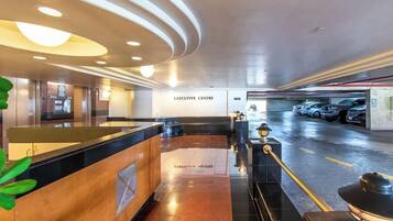 An executive center with a reception desk, a notice board, and a parking area with cars.