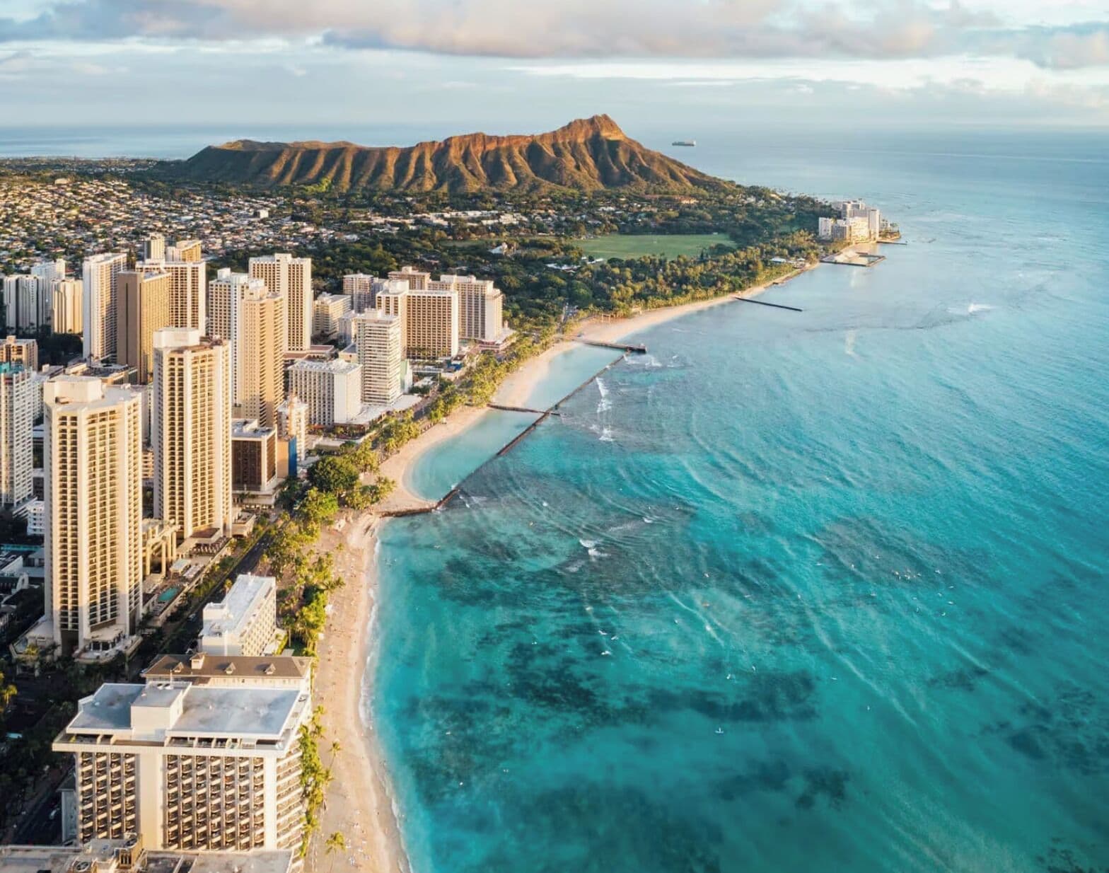 An aerial view of a coastal city with high-rise buildings, a beach, and a mountain in the background.