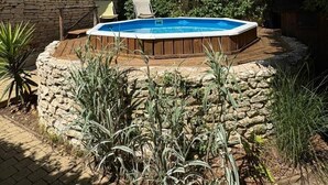 En trädgård med en pool, stenmurar och olika typer av växter.