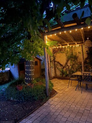 A covered outdoor patio with a table and chairs, surrounded by greenery and a wooden structure. - Le Logis du Coteau - SAINT-MARTIN-LA-PALLU (SAINT-MARTIN-LA-PALLU)