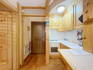 A compact kitchen with wooden cabinets, a stove, and a sink. - Apartment Anny by Interhome (Canazei)