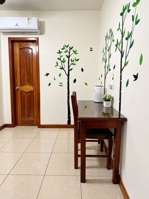 Un comedor con una mesa y sillas de madera, un aire acondicionado instalado en la pared y una puerta.