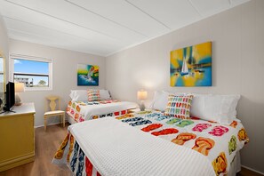 A hotel room with two beds, a desk, a chair, and artwork on the walls. - Direct Oceanfront Condo on Ocean City’s Boardwalk (Ocean City)