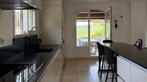 A modern kitchen with a black countertop, white cabinets, and a view to an outdoor patio. - Family villa with a pool, 2.5 km from the center of Aix-en-Provence ⭐⭐⭐⭐⭐ (Aix-en-Provence)