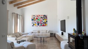 A modern living room with a sectional sofa, a round coffee table, a fireplace, and a colorful abstract painting on the wall. - Family villa with a pool, 2.5 km from the center of Aix-en-Provence ⭐⭐⭐⭐⭐ (Aix-en-Provence)