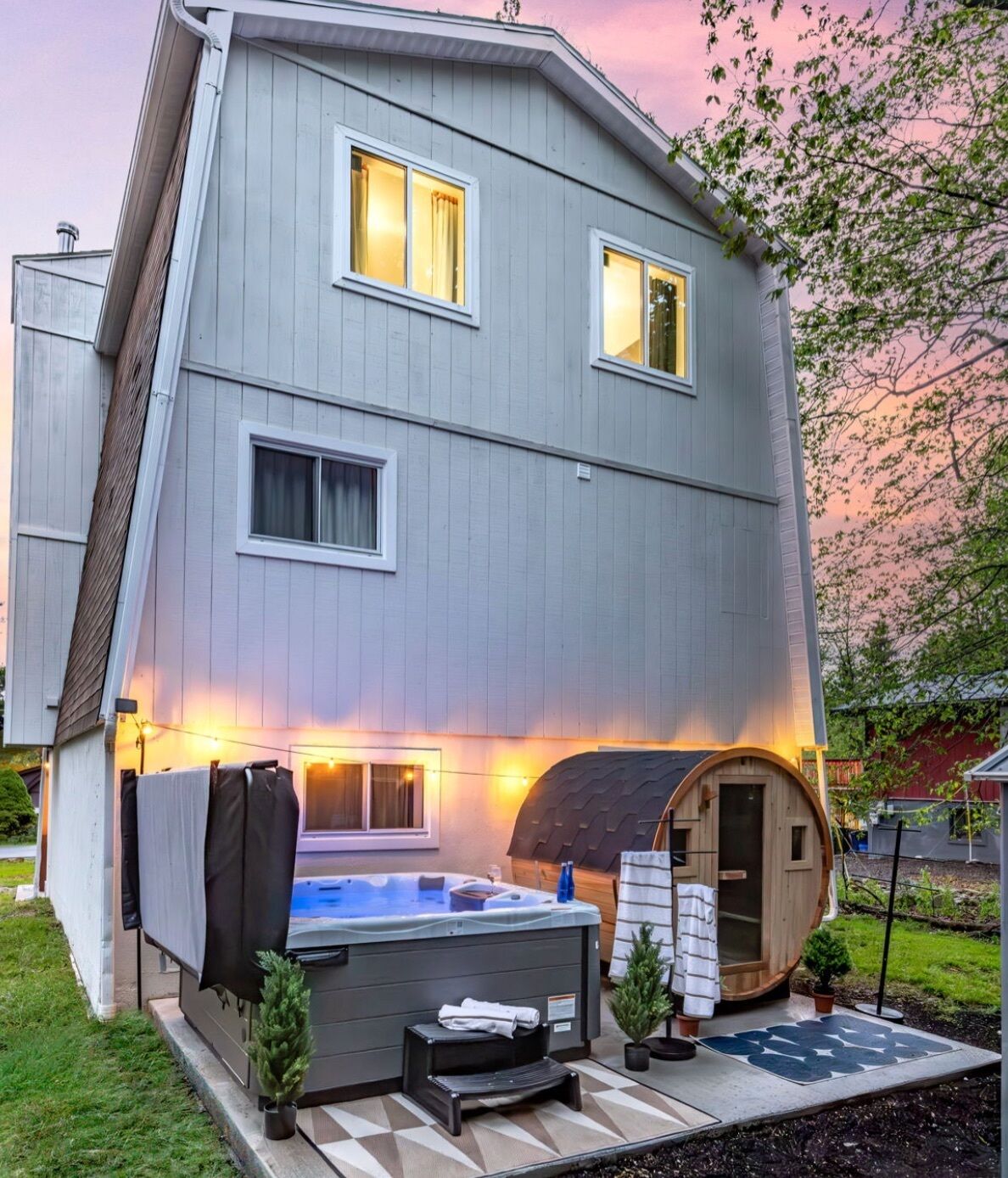 Ein zweistöckiges Haus mit Whirlpool, einem Holzfassbauwerk und einem kleinen Garten.