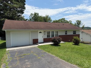 Ein eingeschossiges Haus mit Garage, einer Veranda und einem kleinen Vorgarten.