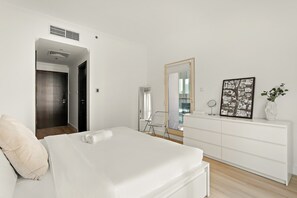 Ein modernes Hotelzimmer mit einem Bett, einer Kommode, einem Spiegel und einem Fenster mit Blick auf die Stadt.