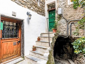 A narrow stone staircase leading to a wooden door with a metal gate, flanked by potted plants and a lantern. - Die Sonnenterasse by Interhome (Badalucco)