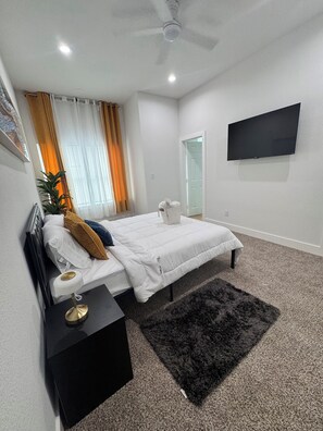 A bedroom with a bed, bedside table, TV, and a ceiling fan. - Delightful family friendly 3-bedroom house  in Houston (Houston)