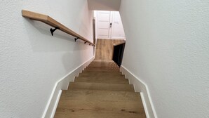 Eine Holztreppe mit weißen Wänden und einer weißen Tür oben.