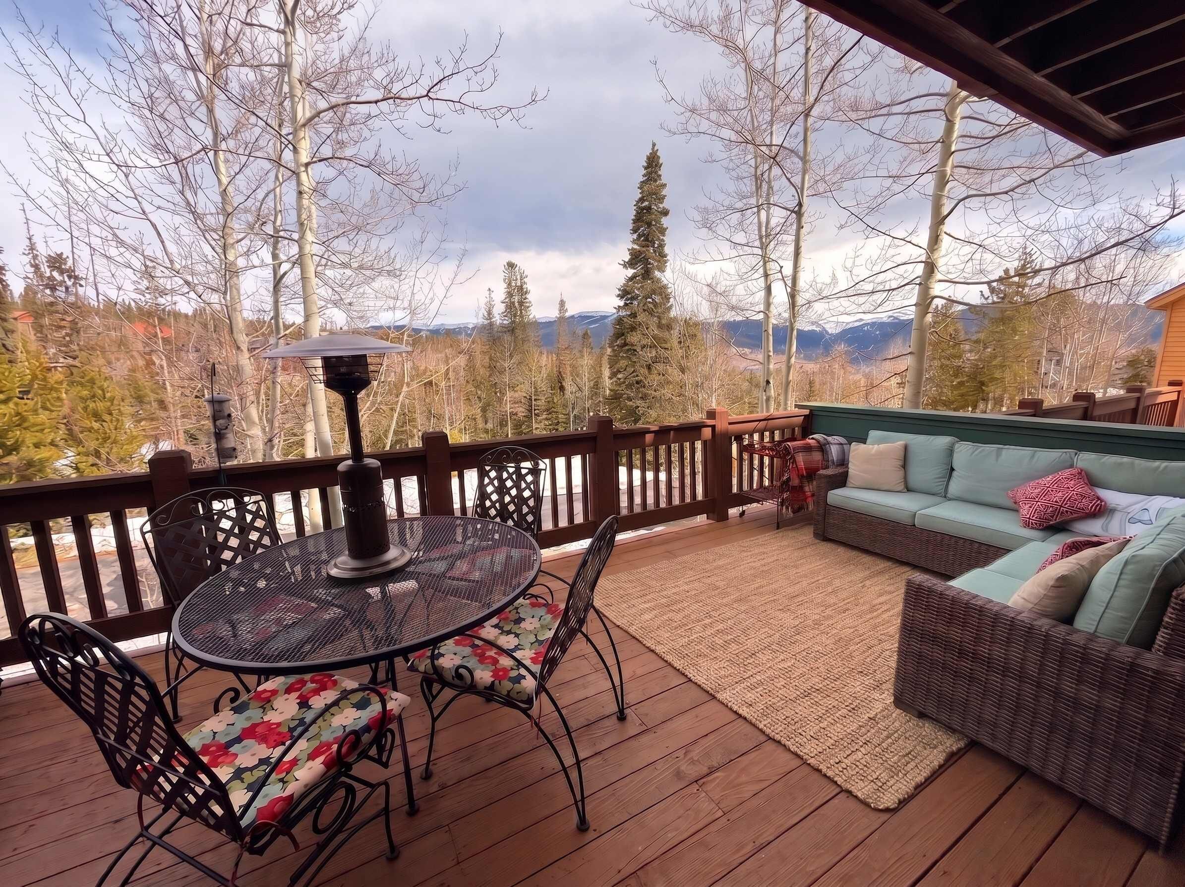 A covered deck with a table and chairs, a sofa, and a view of mountains.
