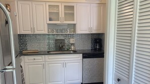 A kitchen with white cabinets, a stainless steel refrigerator, a coffee maker, and a patterned backsplash. - Sunny Sarasota Escape/ Minutes away from Siesta Key & Downtown (Sarasota)