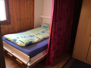 A small, single-bed room with a wooden wall, a white ceiling, and a red curtain. - Almenrausch 2. OG Süd-Ost Appartement/Fewo, Dusche und Bad, WC by Interhome (Riederalp)