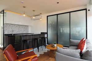 A modern living space with a kitchen, a dining area with a round table, and a seating area with a sofa and chairs. - w* | Enchanting 2BR w/ Balcony in Miraflores (Miraflores)