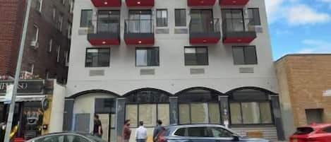 A multi-story building with balconies, a garage entrance, and a clear sky.