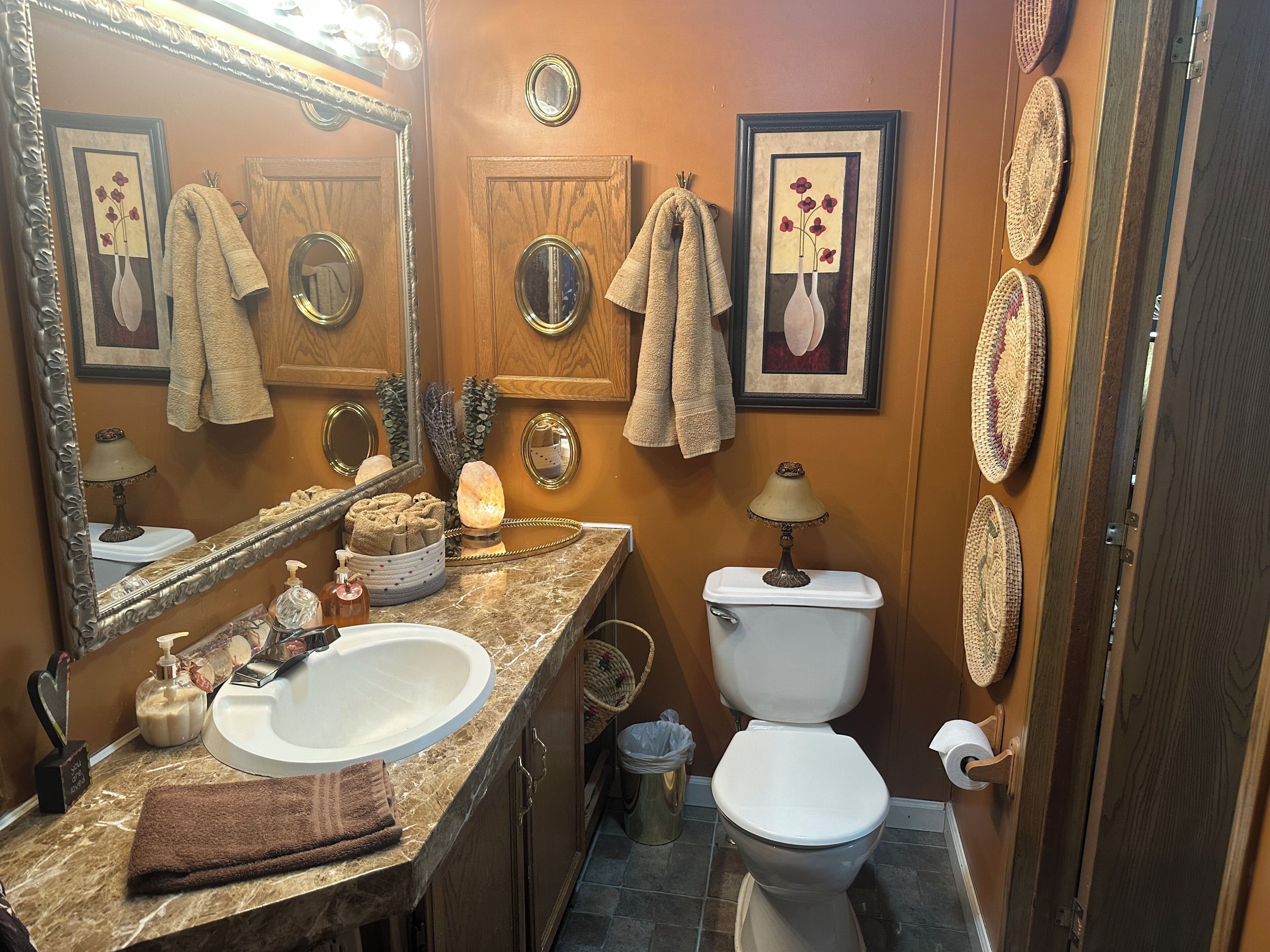 A bathroom with a marble sink, a toilet, and a large mirror.