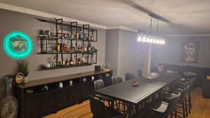 A bar area with shelves of liquor bottles, a neon sign, a dining table with chairs, and a ceiling fan. - Bellerive Country Club 3.2 mi to BMW Tourney Golf with Outdoor Bar Chesterfield (Chesterfield)