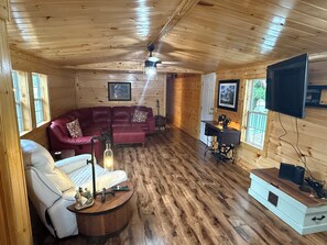A wooden interior with a sofa, a table with a lamp, and a television mounted on the wall. - O-TOWN OASIS!  Near Oneida Baptist Institute & 10 miles from Manchester, KY (Oneida)