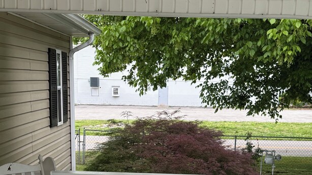 A porch with a white railing, a rocking chair with a red cushion, and a view of a street and greenery. - O-TOWN OASIS!  Near Oneida Baptist Institute & 10 miles from Manchester, KY (Oneida)