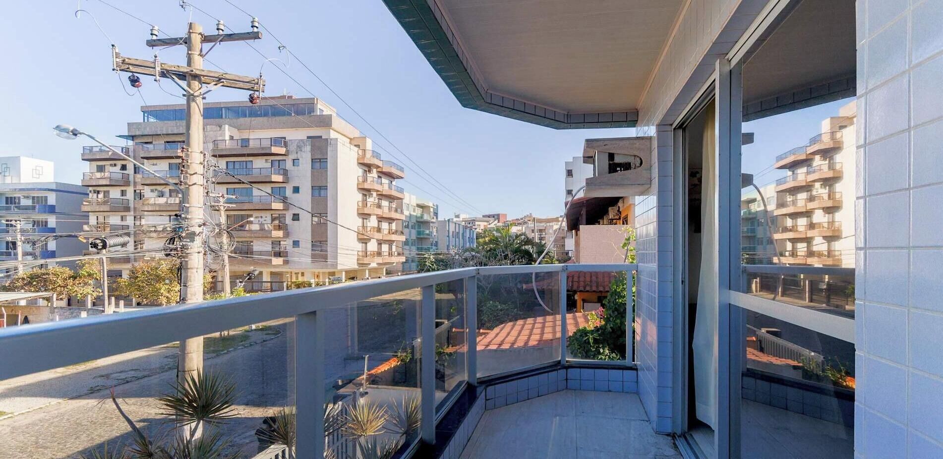 A balcony with a view of a residential area, including buildings and a street.