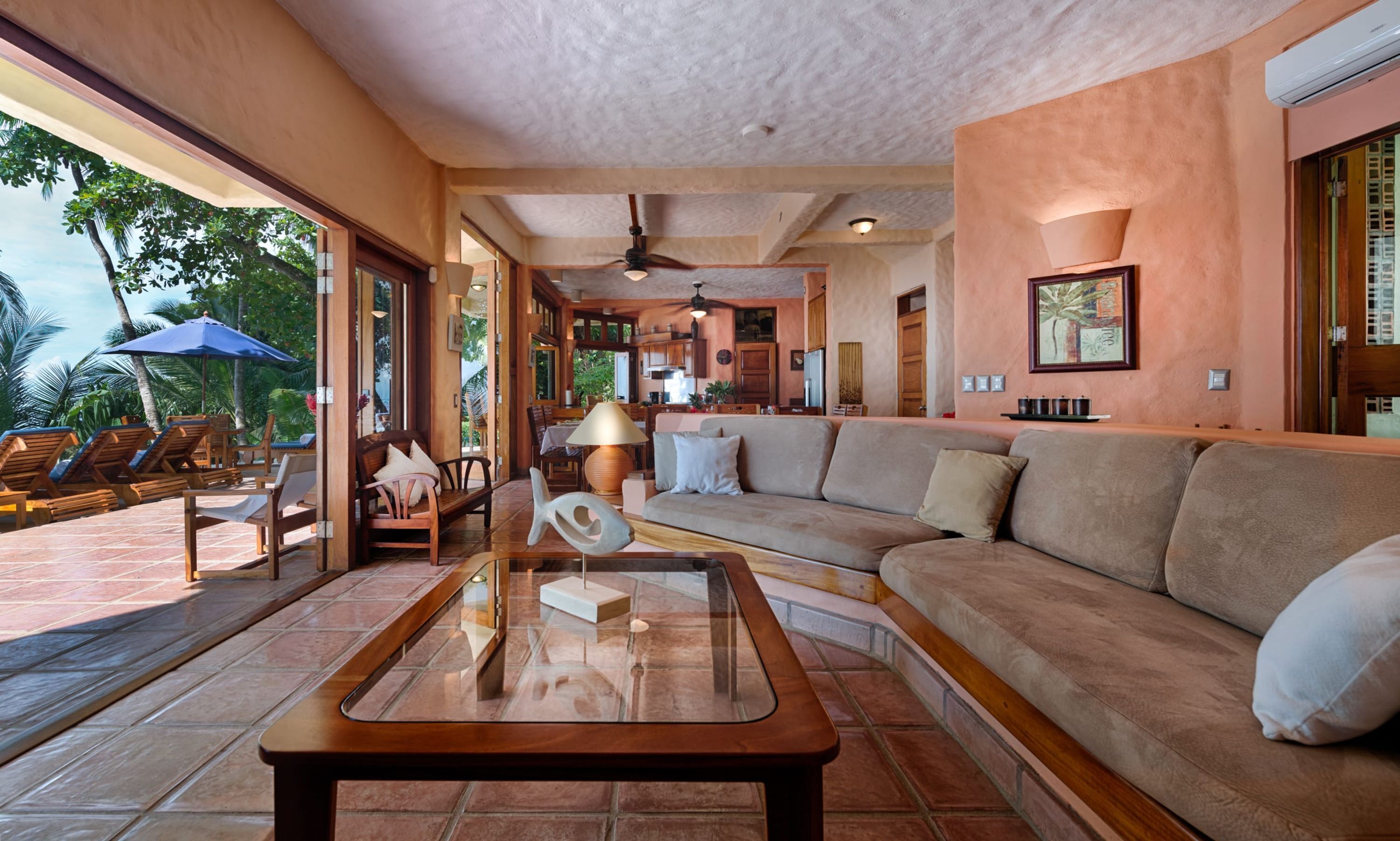 A spacious living area with a sofa, lounge chairs, a coffee table, and a ceiling fan.