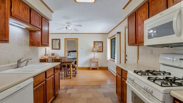 Una cucina con mobili in legno, un piano cottura bianco e un'area pranzo con tavolo e sedie.