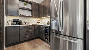Una cucina moderna con mobili scuri, elettrodomestici in acciaio inossidabile e una cantinetta per vini integrata.