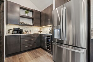 A modern kitchen with dark cabinetry, stainless steel appliances, and a built-in wine cooler. - Lakefront Mansion | Swim Spa, Dock, Kayaks & Games (Long Pond)