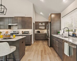 A modern kitchen with dark wood cabinets, stainless steel appliances, and a marble countertop. - Lake House Mansion | Dock+Kayaks+FirePit+Swim Spa (Long Pond)