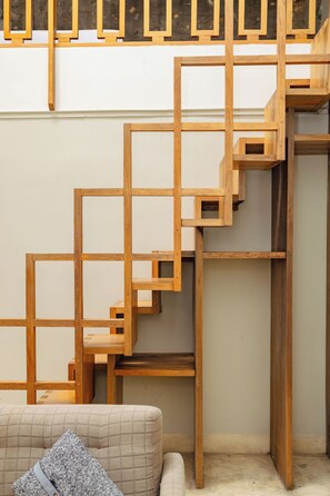 Un interior moderno con una escalera de madera, una zona de estar acolchada y una pared lisa.