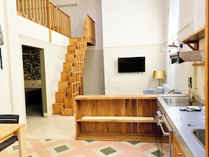 Una cocina moderna con escalera de madera, televisor de pantalla plana y zona de comedor.