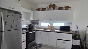 Una cucina moderna con mobili bianchi, un frigorifero in acciaio inossidabile, un forno a microonde e una macchina da caffè.