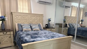 Una camera da letto con un letto, comodini, uno specchio e una cassettiera.