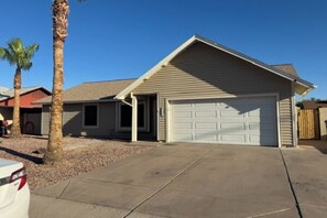 Einbungalow mit Garage, Palmen und blauem Himmel.