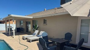 A poolside area with lounge chairs, a table, and a covered patio. - Private Mesa Guest Suite |Shared Pool, Patio & BBQ (Mesa)