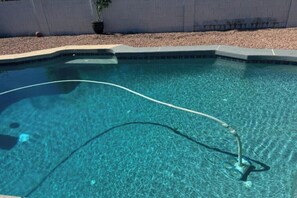Ein klares Schwimmbecken mit sichtbarem Schlauch und Beckenrand aus Kies.