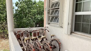 Varias bicicletas están estacionadas en un balcón con vista a árboles y un edificio.
