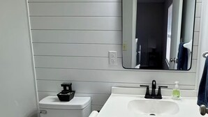 Ein Badezimmer mit Toilette, Waschbecken, Spiegel und Mülleimer.