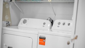 Een voorzichtszicht van een witte wasmachine met bedieningspaneel, een droger en een label op de deur.