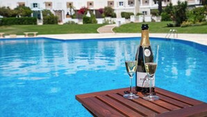 A poolside setting with a wooden table, a bottle of champagne, and two glasses. - Beach villa with ocean view and rooftop cinema (Guia)