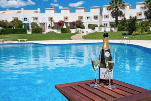 Ein Poolbereich mit einem Holztisch, einer Champagnerflasche und zwei Gläsern.