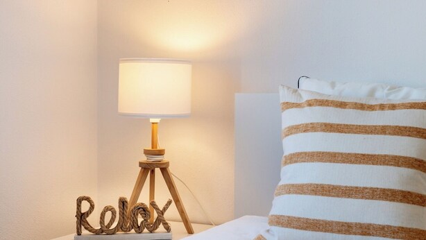 A bedside table with a lamp, a pillow, and a decorative word 'Relax' on a small stand. - Beach villa with ocean view and rooftop cinema (Guia)
